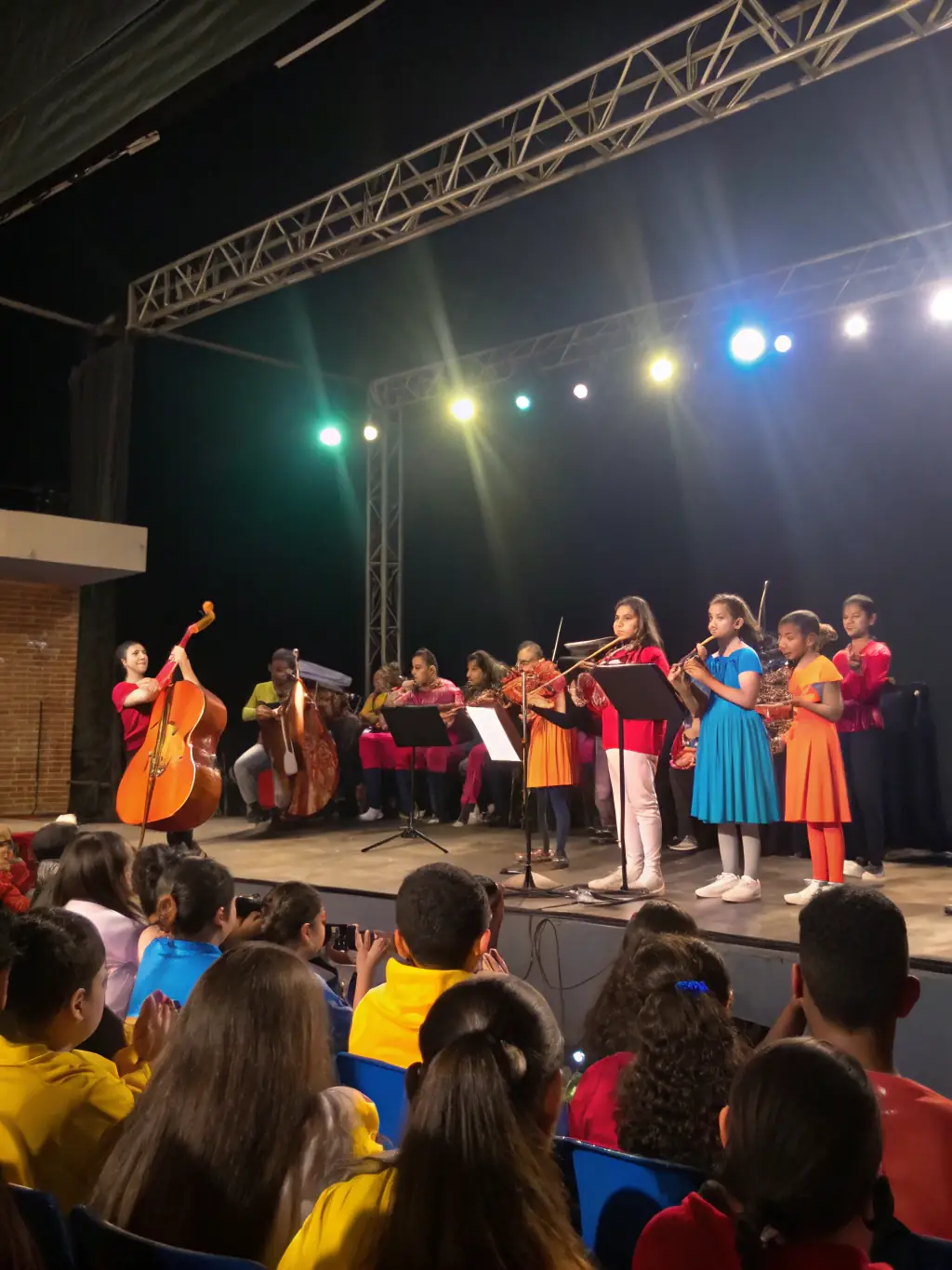 A photo of young musicians performing on stage at a local community center during an AG MUSIC-sponsored event. The image should highlight the energy and excitement of the performance, as well as the supportive audience.